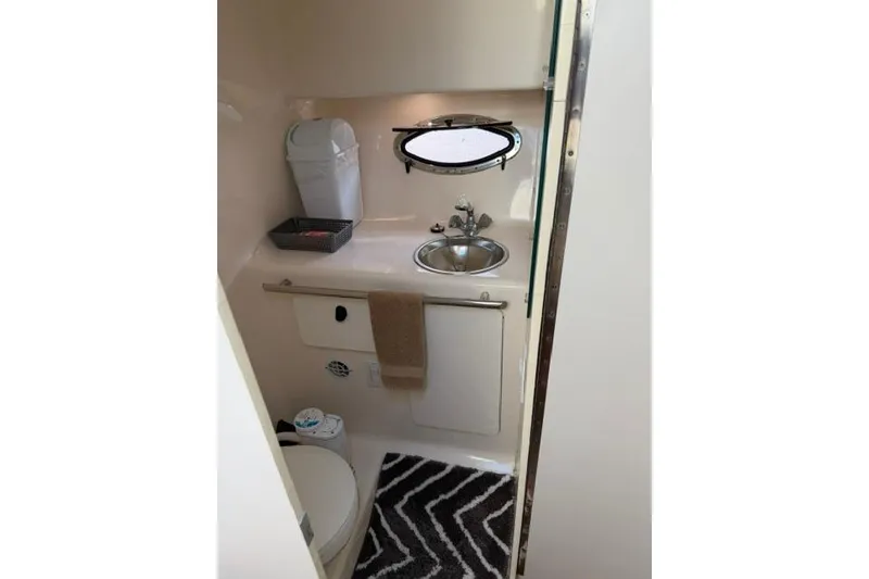 Slide: The Image of Compact bathroom in a 2002 Tiara 29 boat, featuring sink, toilet, and storage. - 8