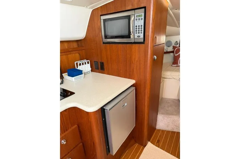 Slide: The Image of Compact kitchen area in a 2002 Tiara 29 boat with microwave and mini fridge. - 10