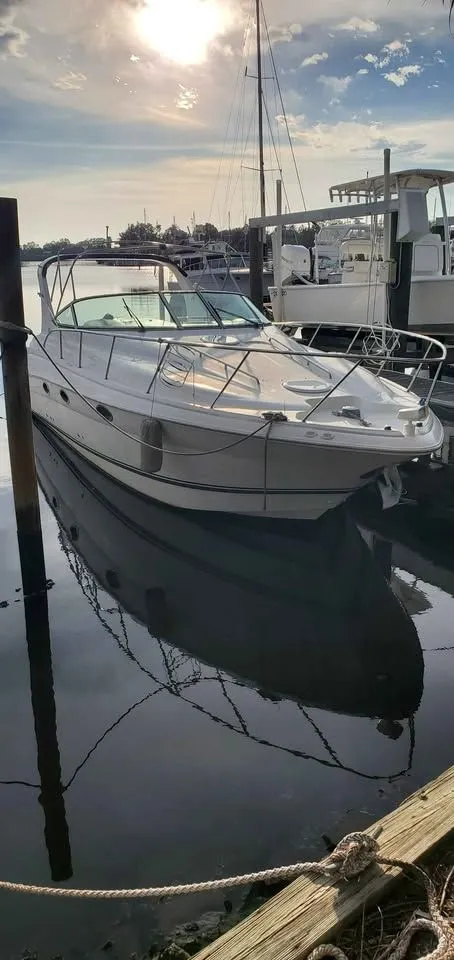 Slide: The Image of A 2002 Wellcraft 3300 Martinique docked in calm waters, reflecting the sky. - 19