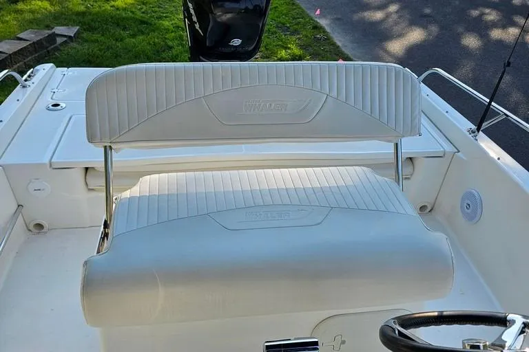 Slide: The Image of 2011 Boston Whaler 230 Dauntless boat interior with cushioned seating and steering wheel. - 12