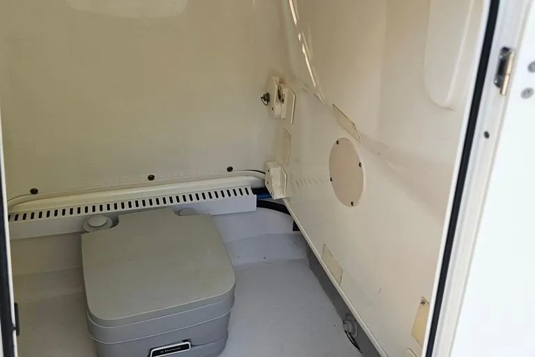 Slide: The Image of Interior of 2011 Boston Whaler 230 Dauntless boat, featuring a compact marine toilet. - 10