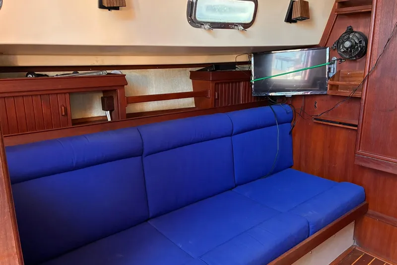 Slide: The Image of Interior of 1991 Island Packet 29 sailboat with blue cushioned seating and wooden cabinetry. - 24
