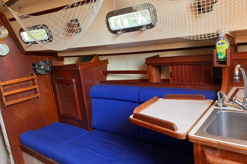 Slide: The Image of Interior of 1991 Island Packet 29 sailboat with blue seating and wooden cabinetry. - 21