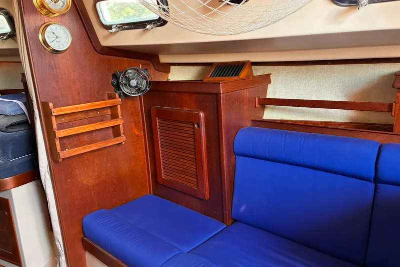 Slide: The Image of Interior of 1991 Island Packet 29 sailboat with blue seating and wooden cabinetry. - 22
