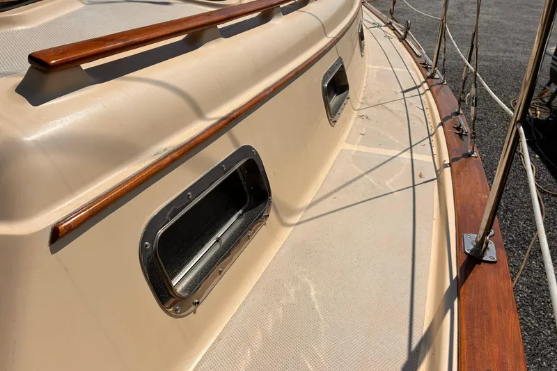 Slide: The Image of 1991 Island Packet 29 sailboat deck with wood trim and porthole. - 10