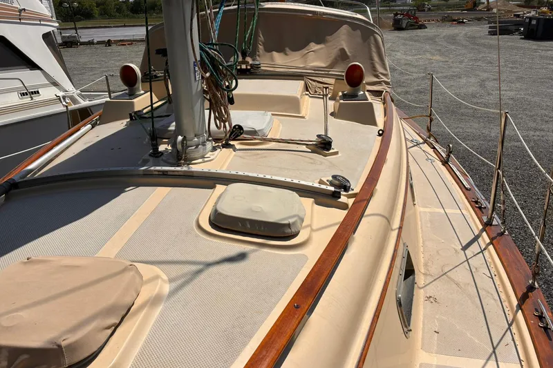 Slide: The Image of 1991 Island Packet 29 sailboat deck with beige covers and wooden trim. - 11