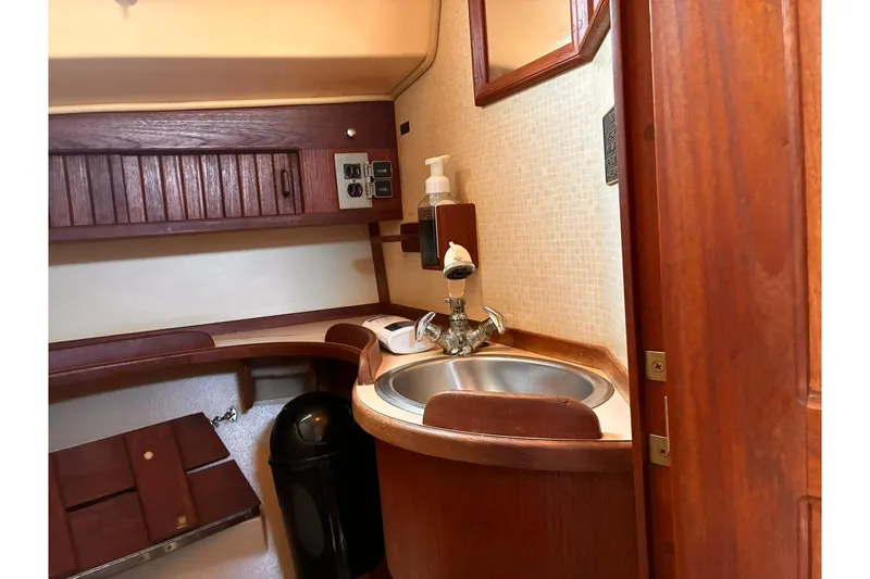 Slide: The Image of 1991 Island Packet 29 yacht interior with wooden cabinetry and compact sink area. - 27