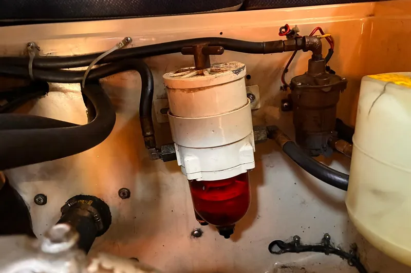 Slide: The Image of Engine compartment of a 1991 Island Packet 29 sailboat, featuring fuel filter and hoses. - 34