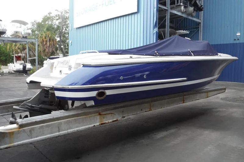 Slide: The Image of 2008 Chris-Craft Launch 25 boat in blue, docked at a marina with a covered deck. - 5