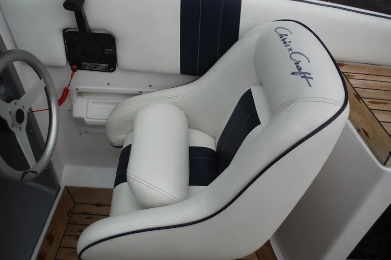 Slide: The Image of 2008 Chris-Craft Launch 25 boat interior with white and navy seating and steering wheel. - 13