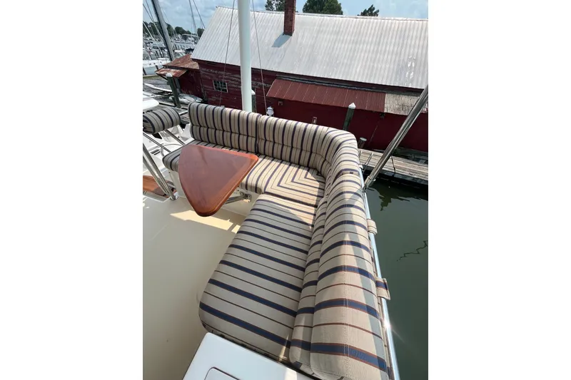 Slide: The Image of Striped seating area on 2018 Sabre 42 Fly Bridge Sedan yacht, docked by a rustic building. - 9