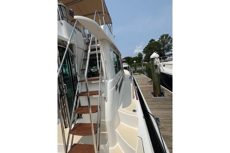 Slide: The Image of 2018 Sabre 42 Fly Bridge Sedan docked, featuring sleek design and wooden steps. - 15