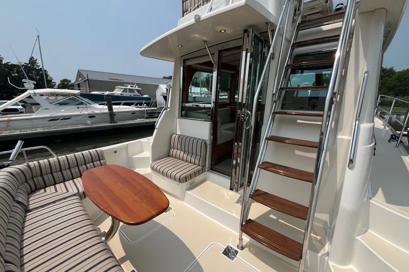 Slide: The Image of 2018 Sabre 42 Fly Bridge Sedan yacht with striped seating and wooden table on deck. - 17