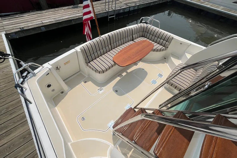 Slide: The Image of 2018 Sabre 42 Fly Bridge Sedan with striped seating and wooden table on deck. - 16