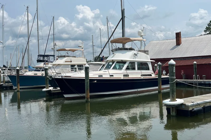 Slide: The Image of 2018 Sabre 42 Fly Bridge Sedan docked at a marina under a cloudy sky. - 2