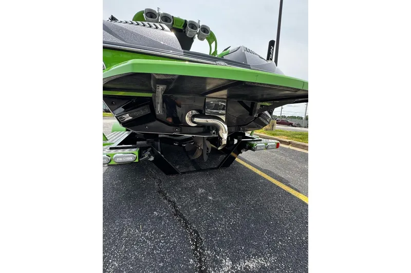 Slide: The Image of 2014 Nautique Super Air Nautique G21 boat rear view, showcasing green hull and exhaust system. - 7