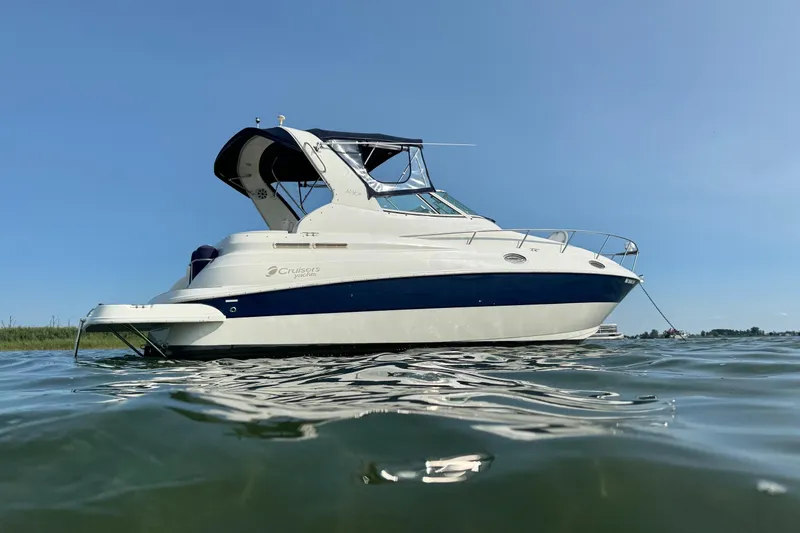 The Image of 2004 Cruisers Yachts 280 CXi Express on calm water under clear blue sky. - 0