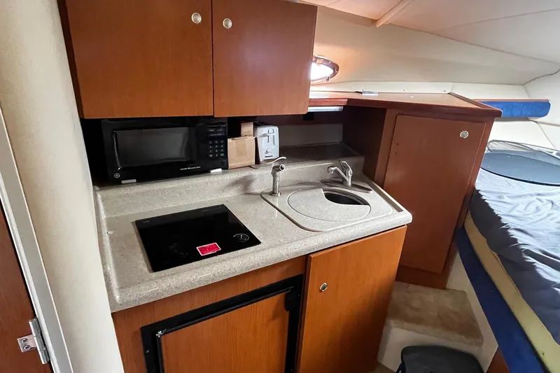 Slide: The Image of 2004 Cruisers Yachts 280 CXi Express cabin kitchen with microwave, sink, and stove. - 21