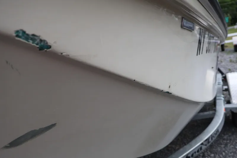 Slide: The Image of 1991 Boston Whaler 170 Montauk boat with visible hull damage on trailer. - 43