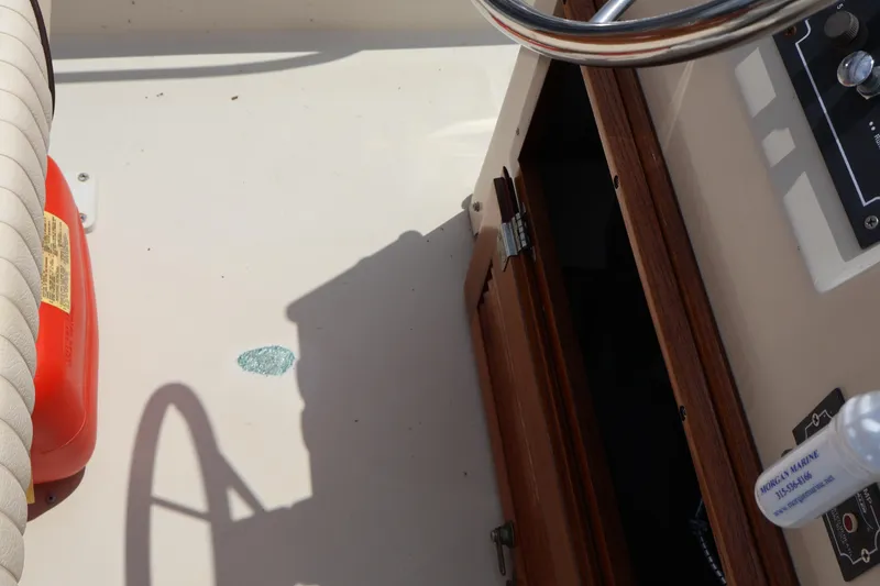 Slide: The Image of Interior view of a 1991 Boston Whaler 170 Montauk boat, featuring steering wheel and storage compartment. - 25