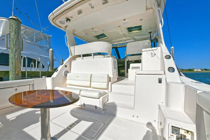 Slide: The Image of 2008 Tiara Yachts 4200 Open cockpit with seating and table, docked under clear blue sky. - 7