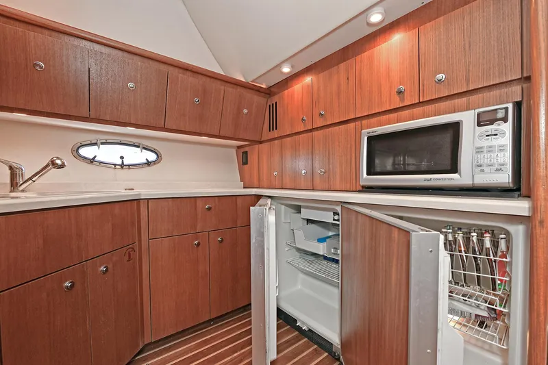 Slide: The Image of 2008 Tiara Yachts 4200 Open galley with wood cabinets, microwave, and open fridge. - 33