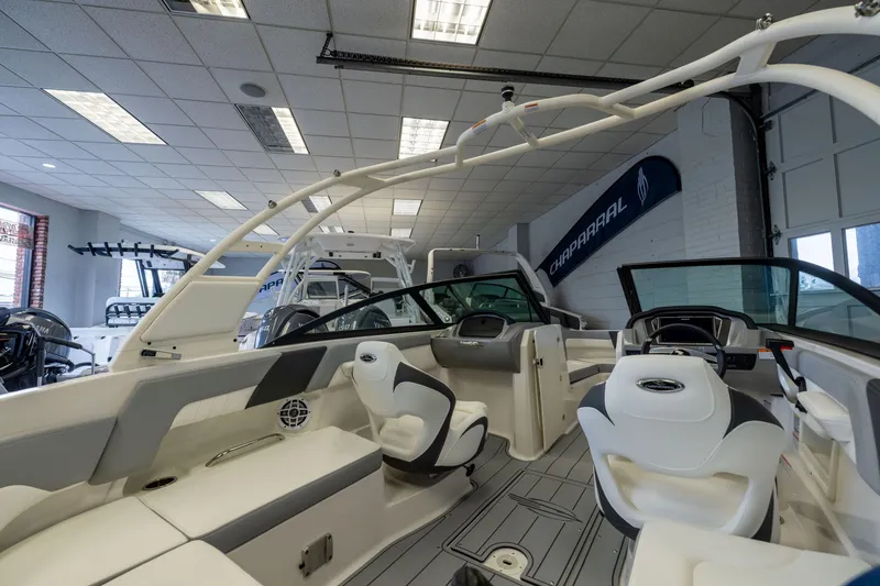 Slide: The Image of 2026 Chaparral 23 SSi OB boat interior in showroom, featuring modern seating and dashboard. - 9