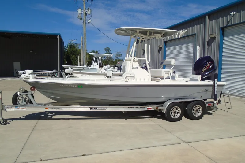 Slide: The Image of 2022 Pathfinder 2200 TRS boat on trailer, parked outside a warehouse. - 6
