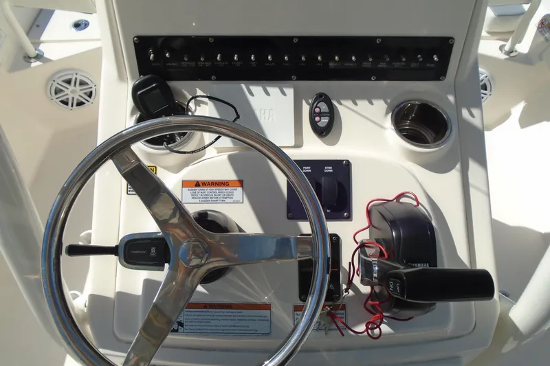 Slide: The Image of Steering console of 2022 Pathfinder 2200 TRS boat with controls and warning labels. - 24