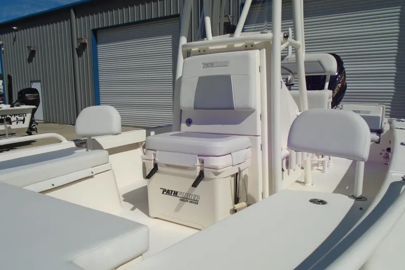 Slide: The Image of 2022 Pathfinder 2200 TRS boat interior with seating and storage, docked near a metal building. - 19