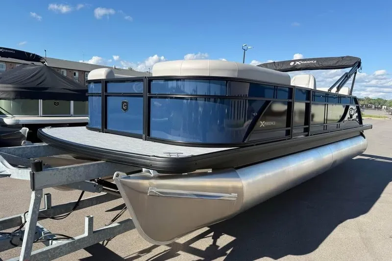 Slide: The Image of 2027 Godfrey EX 2286 SFLX pontoon boat on trailer, under clear blue sky. - 2