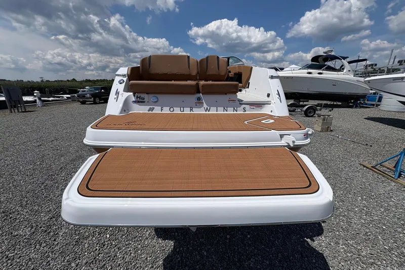 Slide: The Image of 2026 Four Winns H6 boat with teak deck, displayed outdoors under a cloudy sky. - 5