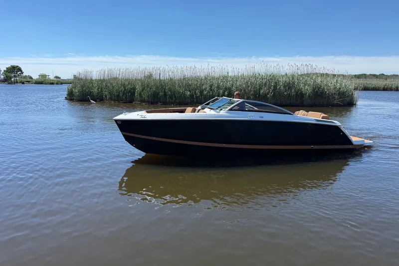 The Image of 2026 Four Winns H6 boat cruising on a calm lake under a clear blue sky. - 0