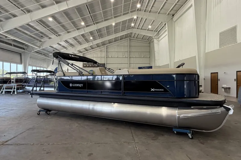 The Image of 2027 Godfrey EX 2286 SBX pontoon boat in spacious indoor showroom. - 0
