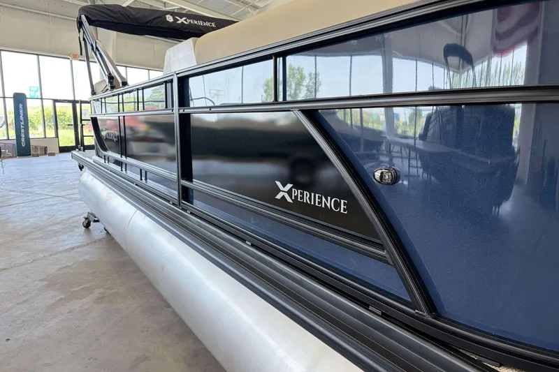 Slide: The Image of 2027 Godfrey EX 2286 SBX pontoon boat in showroom, featuring sleek design and "Xperience" branding. - 12