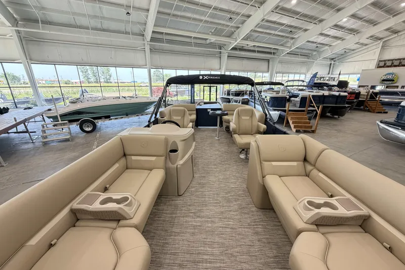 Slide: The Image of 2027 Godfrey EX 2286 SBX pontoon boat interior in showroom, featuring beige seating and modern design. - 3