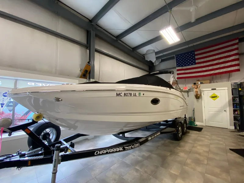 Slide: The Image of A 2020 Chaparral 24 SSI boat on a trailer inside a garage. - 2