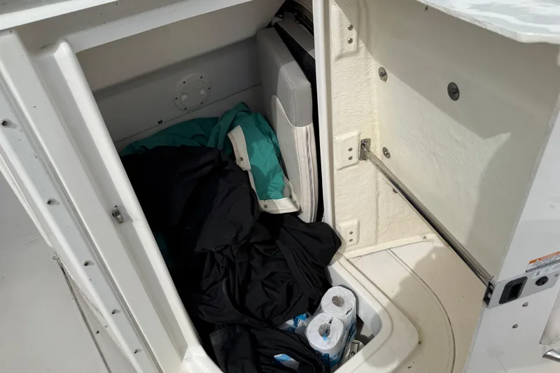 Slide: The Image of Storage compartment of 2017 Robalo R242 Center Console boat with clothing and supplies. - 35