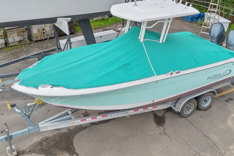 Slide: The Image of 2017 Robalo R242 Center Console boat with teal cover on trailer. - 8