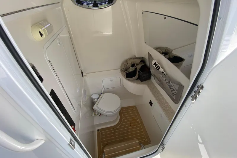 Slide: The Image of 2021 Regulator 28 boat interior with compact bathroom, featuring toilet and storage. - 47