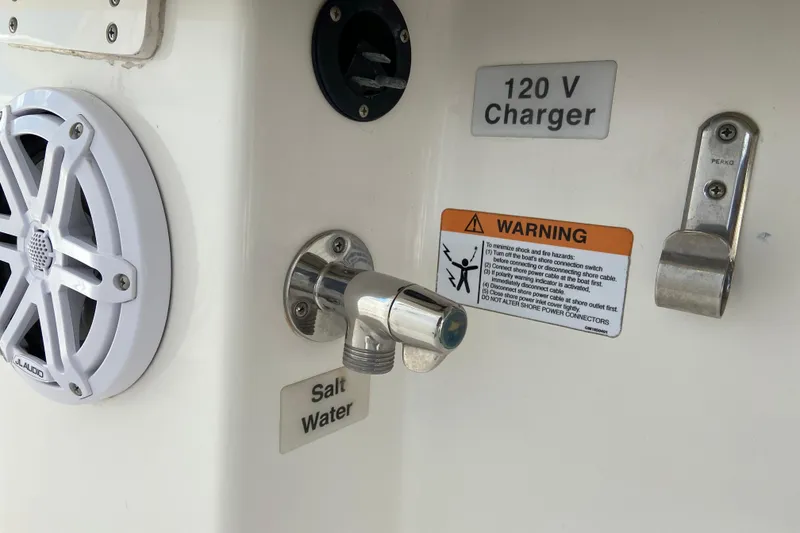 Slide: The Image of 2021 Regulator 28 boat features: JL Audio speaker, 120V charger, saltwater faucet, and safety warning. - 24