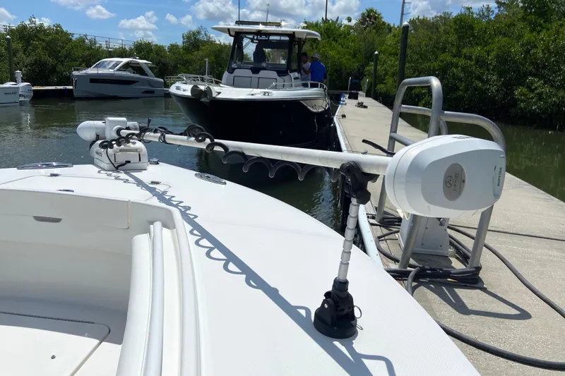 Slide: The Image of 2021 Regulator 28 boat docked with trolling motor, surrounded by other boats and greenery. - 35