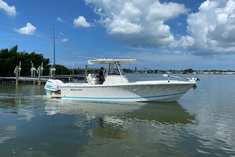 Slide: The Image of 2021 Regulator 28 boat cruising on calm waters under a partly cloudy sky. - 7