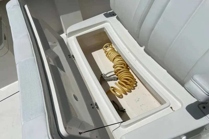 Slide: The Image of Open storage compartment on 2021 Regulator 28 boat with coiled yellow hose. - 50