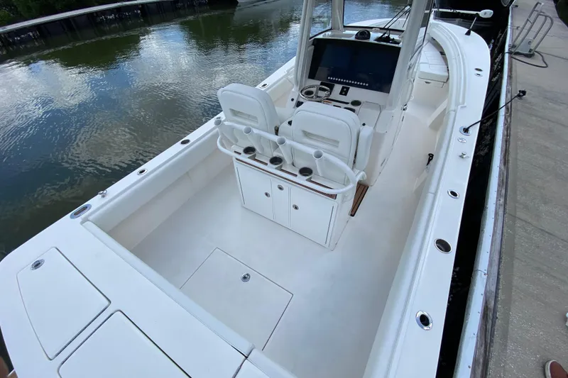 Slide: The Image of 2021 Regulator 28 boat interior with helm, seating, and storage, docked by calm water. - 13