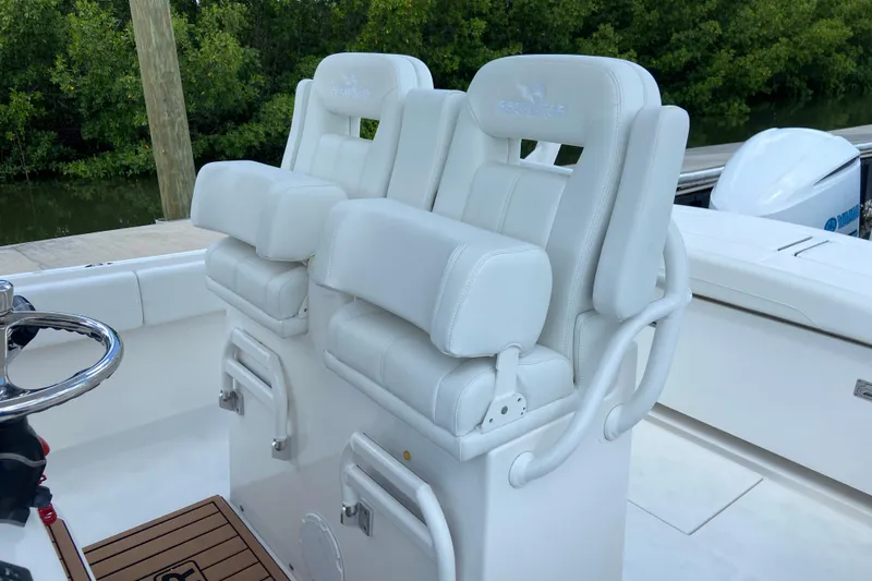 Slide: The Image of 2021 Regulator 28 boat with white cushioned helm seats and steering wheel. - 25