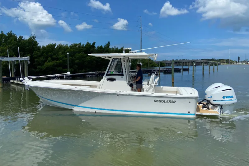 Slide: The Image of 2021 Regulator 28 boat with Yamaha engines on calm water under blue sky. - 2