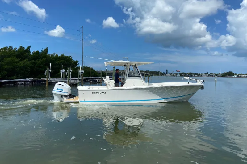 Slide: The Image of 2021 Regulator 28 boat cruising on calm waters under a clear blue sky. - 8