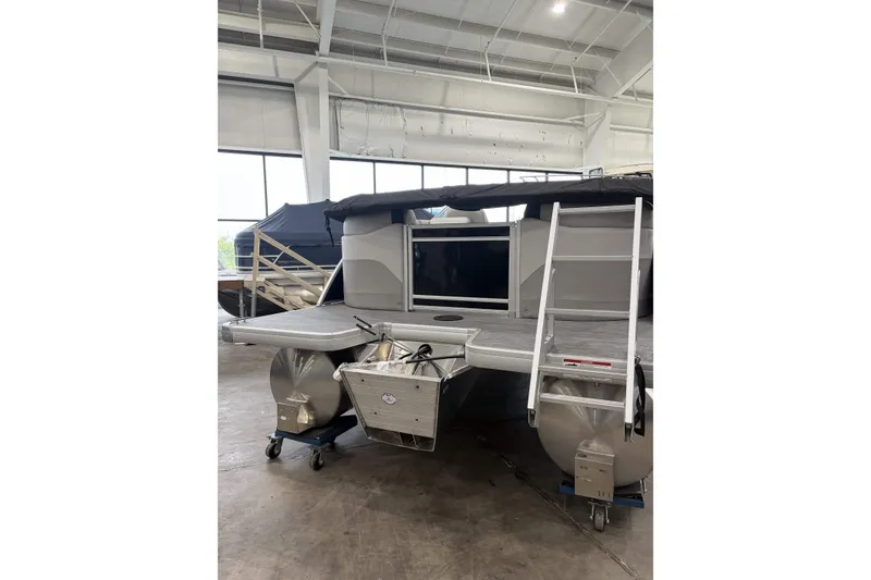 Slide: The Image of 2026 Godfrey Sweetwater 2286 SB pontoon boat in showroom, featuring rear deck and ladder. - 6