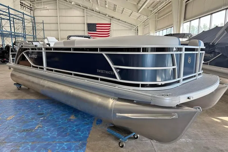 The Image of 2026 Godfrey Sweetwater 2286 SB pontoon boat in a showroom with American flag. - 0